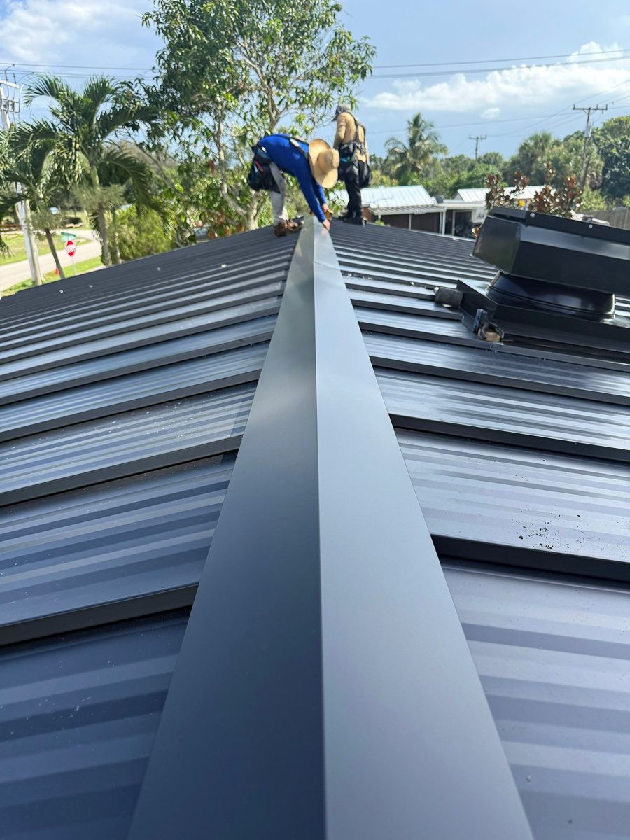 Roofer working along the ridge of a new standing-seam metal roof
