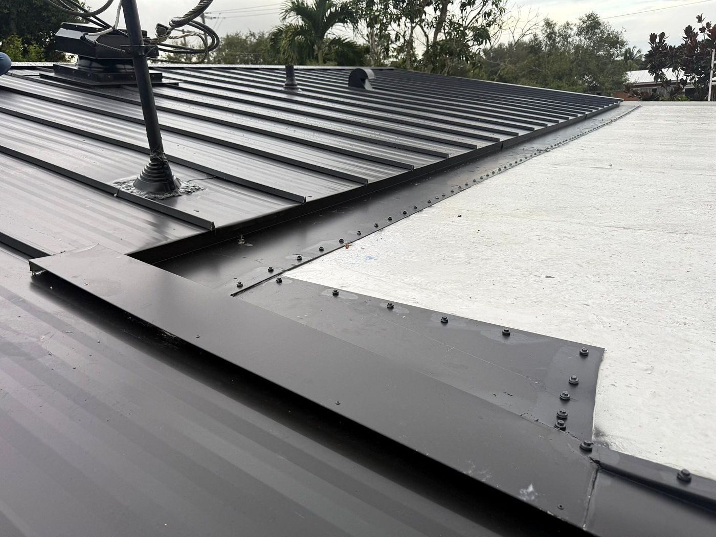 Detail of metal flashing and fasteners where a metal roof meets a flat section
