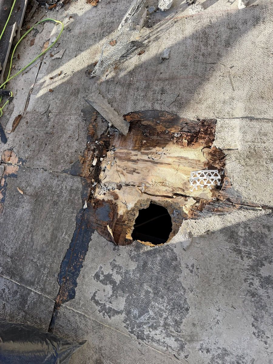 Rotted roof decking with a hole through it, found under the membrane