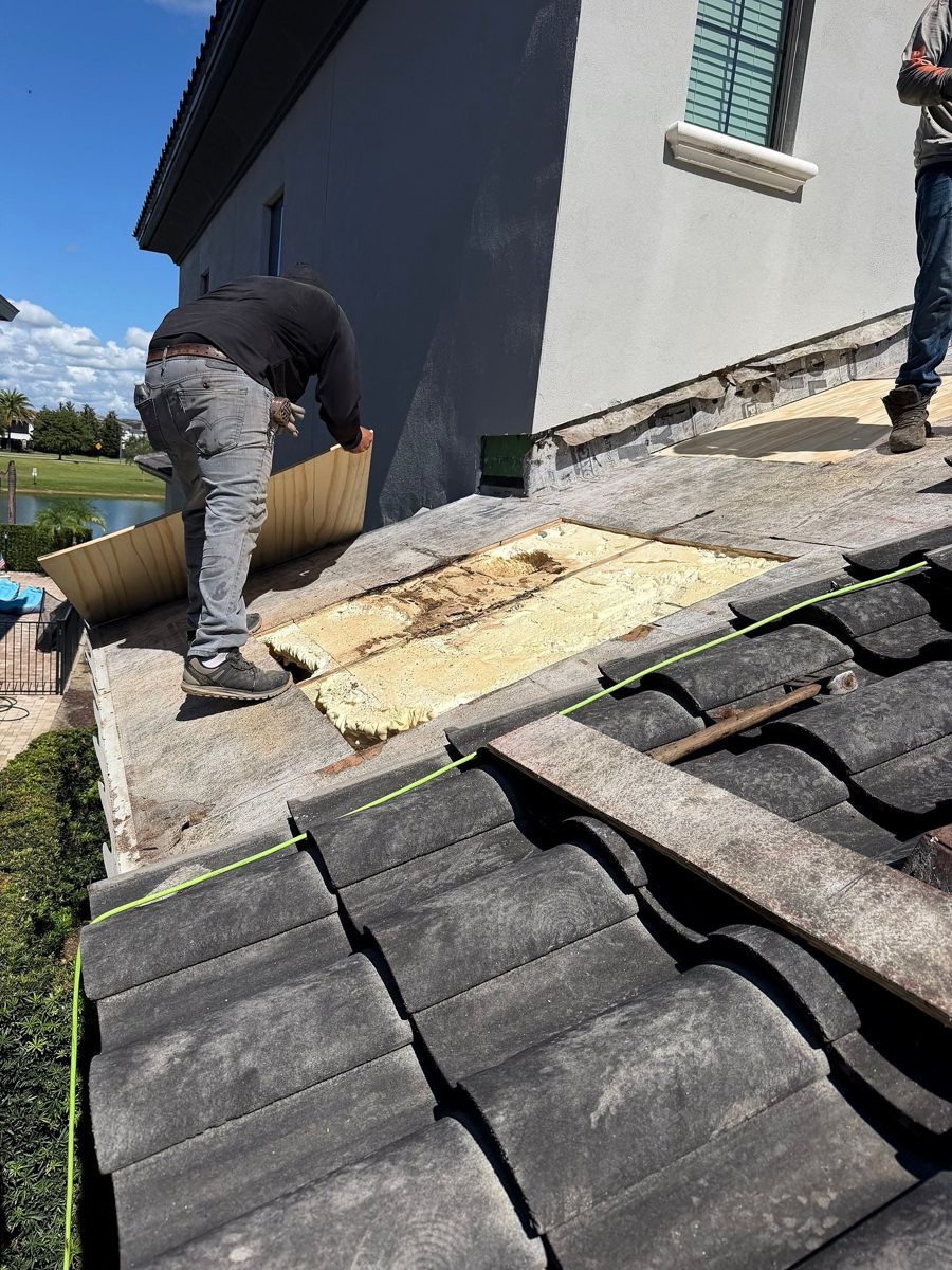 Roofer opening up a section of tile roof to inspect the decking and insulation beneath